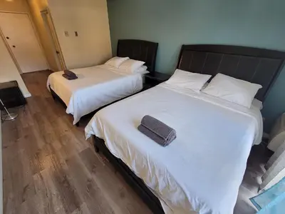 two beds in a room with white sheets at Great Location Double Queen Bed Unit in Los Angeles