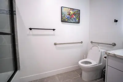 a bathroom with a toilet and a painting on the wall at Stylish Private Room by Downtown LA with Private Parking in Los Angeles