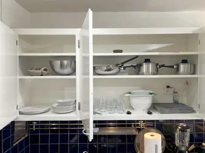 a kitchen with white cabinets with plates and utensils at Seabreeze Hideaway one bedroom in Los Angeles
