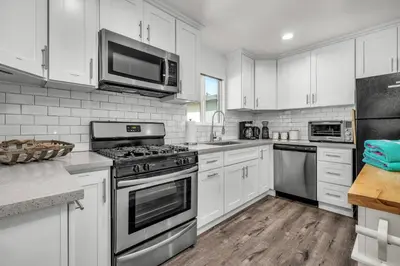 a kitchen with white cabinets and stainless steel appliances at Walgrove Guest House in Los Angeles