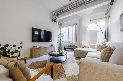 a living room with a couch and a tv at Industrial Style 2BR Condo Downtown LA With Rooftop! in Los Angeles
