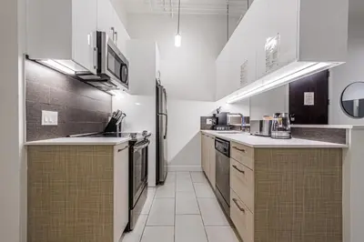 a kitchen with white counters and a refrigerator at Industrial Style 2BR Condo Downtown LA With Rooftop! in Los Angeles