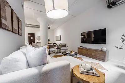 a living room with a white couch and a tv at Industrial Style 2BR Condo Downtown LA With Rooftop! in Los Angeles