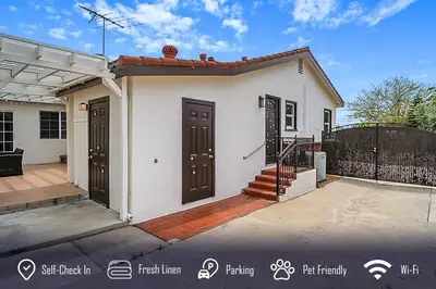 a small white house with brown doors on a driveway at 6BR 3BA Home near Disneyland in Anaheim