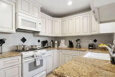 a white kitchen with white cabinets and a sink at Blue Haven Solar Pool Heat Parking Billiards in Long Beach