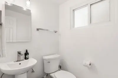 a white bathroom with a toilet and a sink at Sunny Daze - Heated Pool - Billiards - Games in Placentia