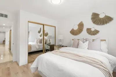 a white bedroom with a large bed and a mirror at Sunny Daze - Heated Pool - Billiards - Games in Placentia