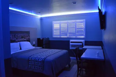 a bedroom with a bed and a table and a blue light at Villa Las Palmas Motel in Barton Heliport