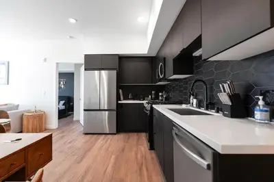 a kitchen with black cabinets and a stainless steel refrigerator at The Hollywood Highline 2 bed Apt WITH FREE PARKING in Hollywood in Los Angeles