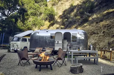 an rv with chairs and a table and a fire at Secluded Pet Friendly Airstream in Calabasas, California in Calabasas