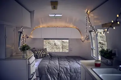 a bedroom with a bed and a sink and lights at Secluded Pet Friendly Airstream in Calabasas, California in Calabasas