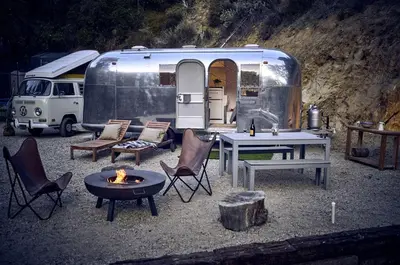 an rv with a table and chairs and a table and a fire at Secluded Pet Friendly Airstream in Calabasas, California in Calabasas