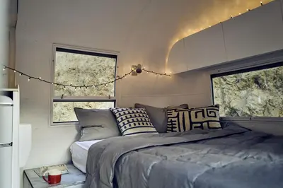 a bedroom with a bed and some windows and lights at Secluded Pet Friendly Airstream in Calabasas, California in Calabasas
