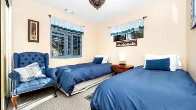 a bedroom with two beds and a blue chair at Charming Cabin for Winter and Water Sports Fans Near Big Bear Lake, California in Arrowbear Lake