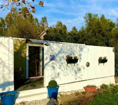 a white shed with two potted plants on it at Fully Refurbished Container in Devore Heights, California, for Glamping Trips on Route 66 in Devore Heights