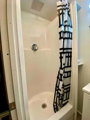 a shower with a black and white shower curtain in a bathroom at Fully Refurbished Container in Devore Heights, California, for Glamping Trips on Route 66 in Devore Heights