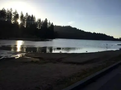 a view of a lake with the sun reflecting on the water at Unique Three-Level Dome near Lake Gregory in Crestline, California in Crestline