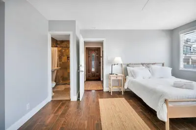 a white bedroom with a large bed and wooden floors at Manhattan Beach Guest Suite in Manhattan Beach