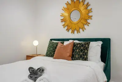 a bedroom with a bed with a mirror and pillows at Overlooking Luxury - Pool Heat - Spa - Games in Pico Rivera