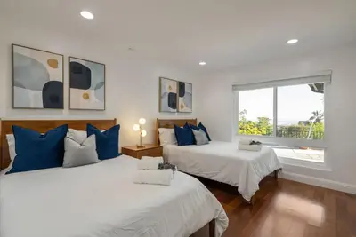 two beds with blue pillows in a room with a window at Overlooking Luxury - Pool Heat - Spa - Games in Pico Rivera
