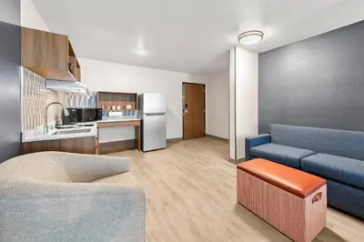 a living room with a blue couch and a kitchen at Everhome Suites San Bernardino - Loma Linda in San Bernardino