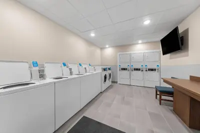 a laundry room with white cabinets and a tv at Everhome Suites San Bernardino - Loma Linda in San Bernardino