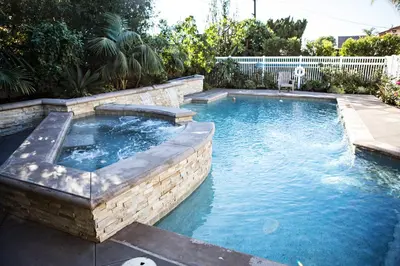 a swimming pool in a backyard with a brick wall at Sensational 6 Bedroom 4 Bathroom Pool Home (3 Master Bedrooms W/bathrooms) in Anaheim