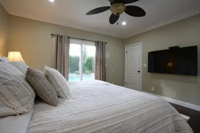 a bedroom with a bed with a ceiling fan and a television at Highly Upgraded, 5 Bed, 45 ba, New Pool w/Jacuzzi, 1/2 mile walk to Disney in Anaheim