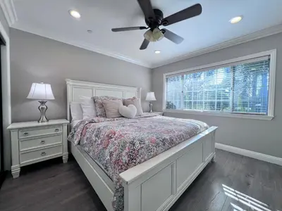 a bedroom with a bed with a ceiling fan and a window at Stunning 8 bedroom 6 bathroom Pool Home in Anaheim