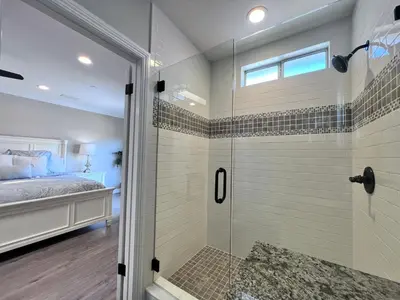 a bathroom with a walk in shower next to a bed at Stunning 8 bedroom 6 bathroom Pool Home in Anaheim