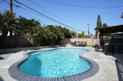a swimming pool in a backyard with chairs around it at Amazing Large Family Home w/Pool, 1 Mile to Disney in Anaheim