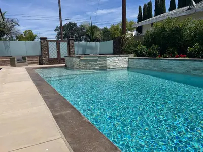 a swimming pool with blue water in a yard at Beautiful Remodel 3 Bedroom 2 bathroom Home with Pool & Jacuzzi in Fullerton