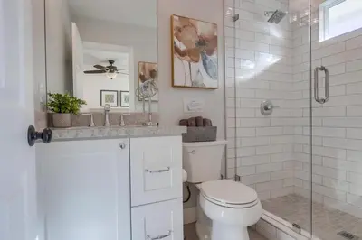 a white bathroom with a toilet and a shower at Beautiful Remodel 3 Bedroom 2 bathroom Home with Pool & Jacuzzi in Fullerton