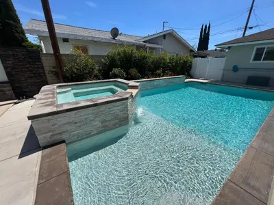 a swimming pool in a backyard with blue water at Beautiful Remodel 3 Bedroom 2 bathroom Home with Pool & Jacuzzi in Fullerton
