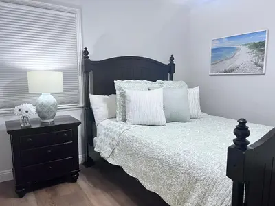 a bedroom with a bed with white pillows and a lamp at Anaheim California, Beautiful Pool Home, Short Walk to Disney in Anaheim