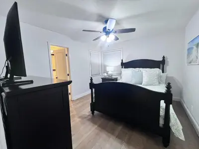 a bedroom with a black bed and a ceiling fan at Anaheim California, Beautiful Pool Home, Short Walk to Disney in Anaheim