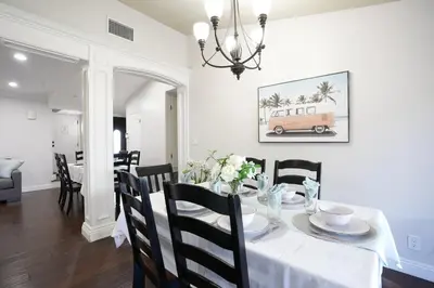a dining room with a table with a white table cloth and a chandelier at Sweet 4 bedroom, 3 bath plus Loft Bedroom, Pool Home in Anaheim