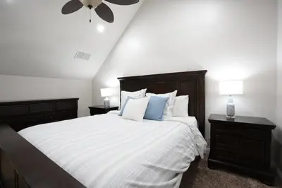 a bedroom with a bed with white sheets and blue pillows at Sweet 4 bedroom, 3 bath plus Loft Bedroom, Pool Home in Anaheim