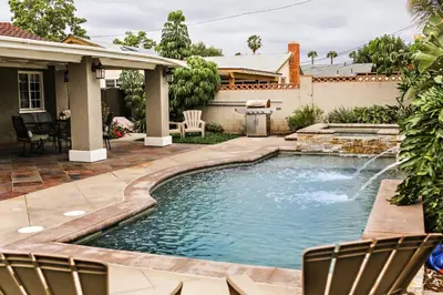 a pool in a yard with chairs and a house at Wonderful 4 Bedroom 3 Bath Pool Home 3/4 Mile To Disney in Anaheim