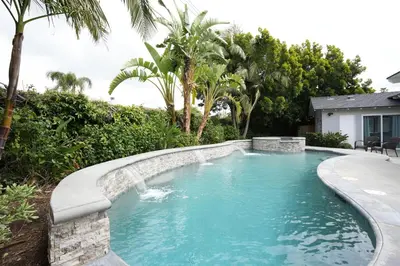a swimming pool with a waterfall in a backyard at 4 bedroom, 3 bathrooms Pool Home in Orange