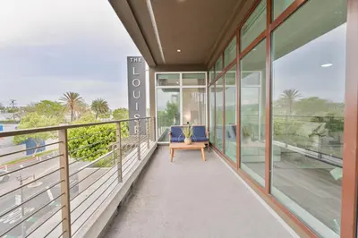 a balcony of a house with glass windows and a blue couch at Glam by the Hollywood Sign 2 Bed Apt WITH FREE EV PARKING, Pool, Gym in Los Angeles