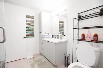 a white bathroom with a toilet and a sink at Glam by the Hollywood Sign 2 Bed Apt WITH FREE EV PARKING, Pool, Gym in Los Angeles