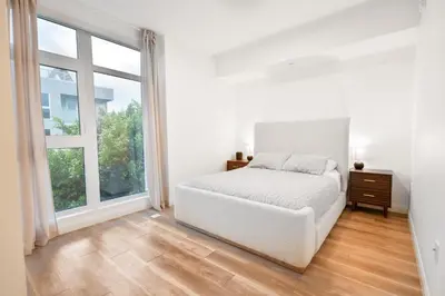 a white bedroom with a bed and a large window at Glam by the Hollywood Sign 2 Bed Apt WITH FREE EV PARKING, Pool, Gym in Los Angeles