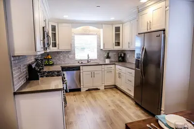 a kitchen with white cabinets and a stainless steel refrigerator at Adorable 3 Bedroom 2 Bath Home in Fullerton