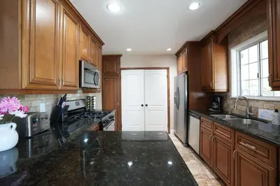 a kitchen with wooden cabinets and a black counter top at Charming Anaheim Home 1/2 Mile Walk to Disney in Anaheim