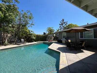 a swimming pool with a table and an umbrella at Gorgeous Pool Home 1/2 Mile Walk to Disney in Anaheim