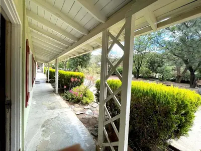 a porch of a house with a fence and flowers at Sierra Pelona Motel in Santa Clarita