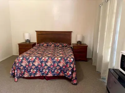 a bedroom with a bed and two dressers and a television at Sierra Pelona Motel in Santa Clarita