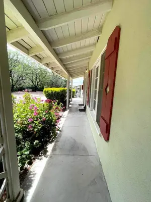 a hallway of a building with a red door and flowers at Sierra Pelona Motel in Santa Clarita