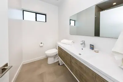 a white bathroom with a toilet and a mirror at Modern 2BR Back House w/ TVs & Full Kitchen in Los Angeles